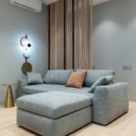 Sofá-cama cinza moderno em ambiente decorado com iluminação suave e parede ripada de madeira