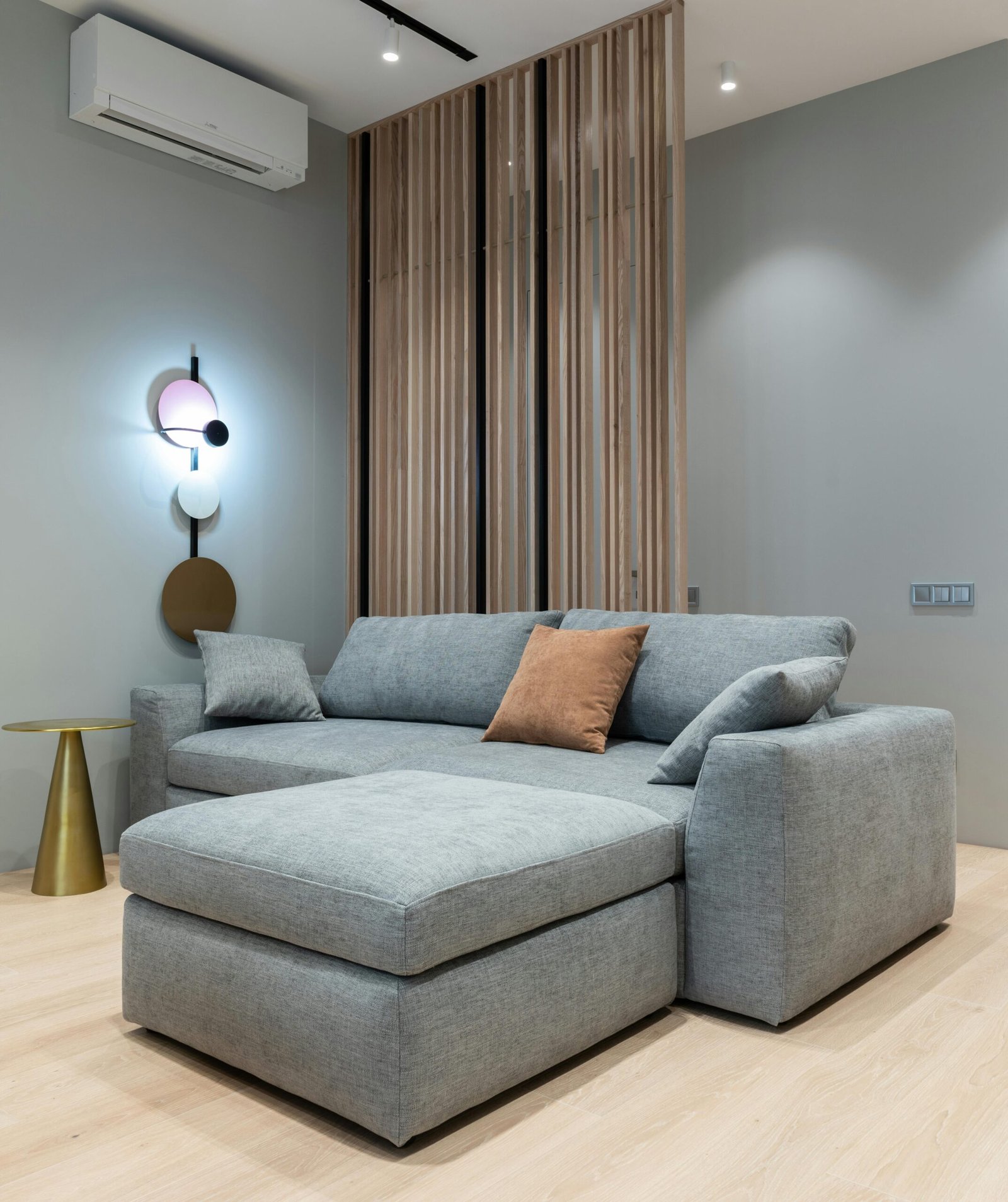 Sofá-cama cinza moderno em ambiente decorado com iluminação suave e parede ripada de madeira