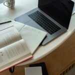 Mesa de trabalho com notebook aberto, livros e café, representando produtividade e rotina profissional em 2025.